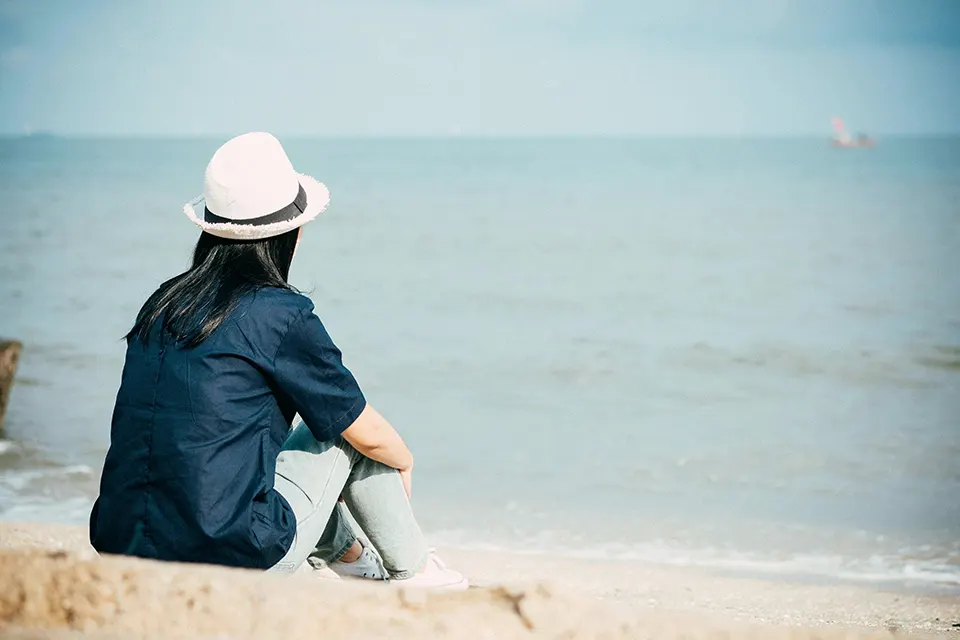 Perdonarse a uno mismo: imagen de una mujer sentada en la playa contemplando el mar